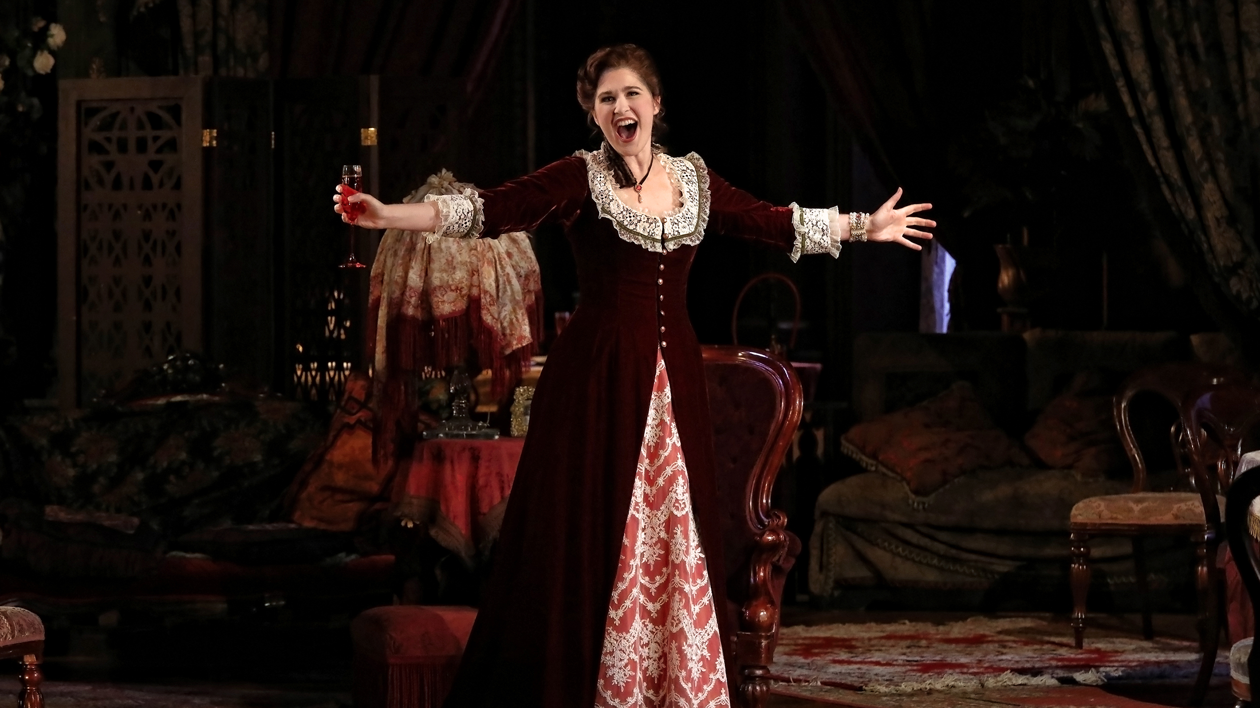 Singer Nicole Car raises a wine glass while singing in a performance of La Traviata at the Sydney Opera House