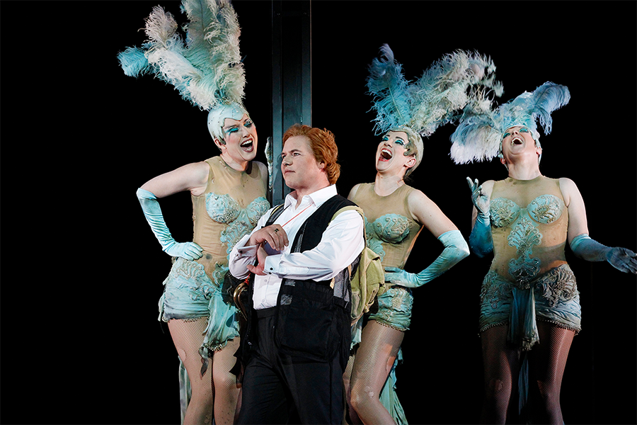Singer Stefan Vinke is surroudned by three singers in showgirl-inspired costumes in a performance of The Ring Cycle.
