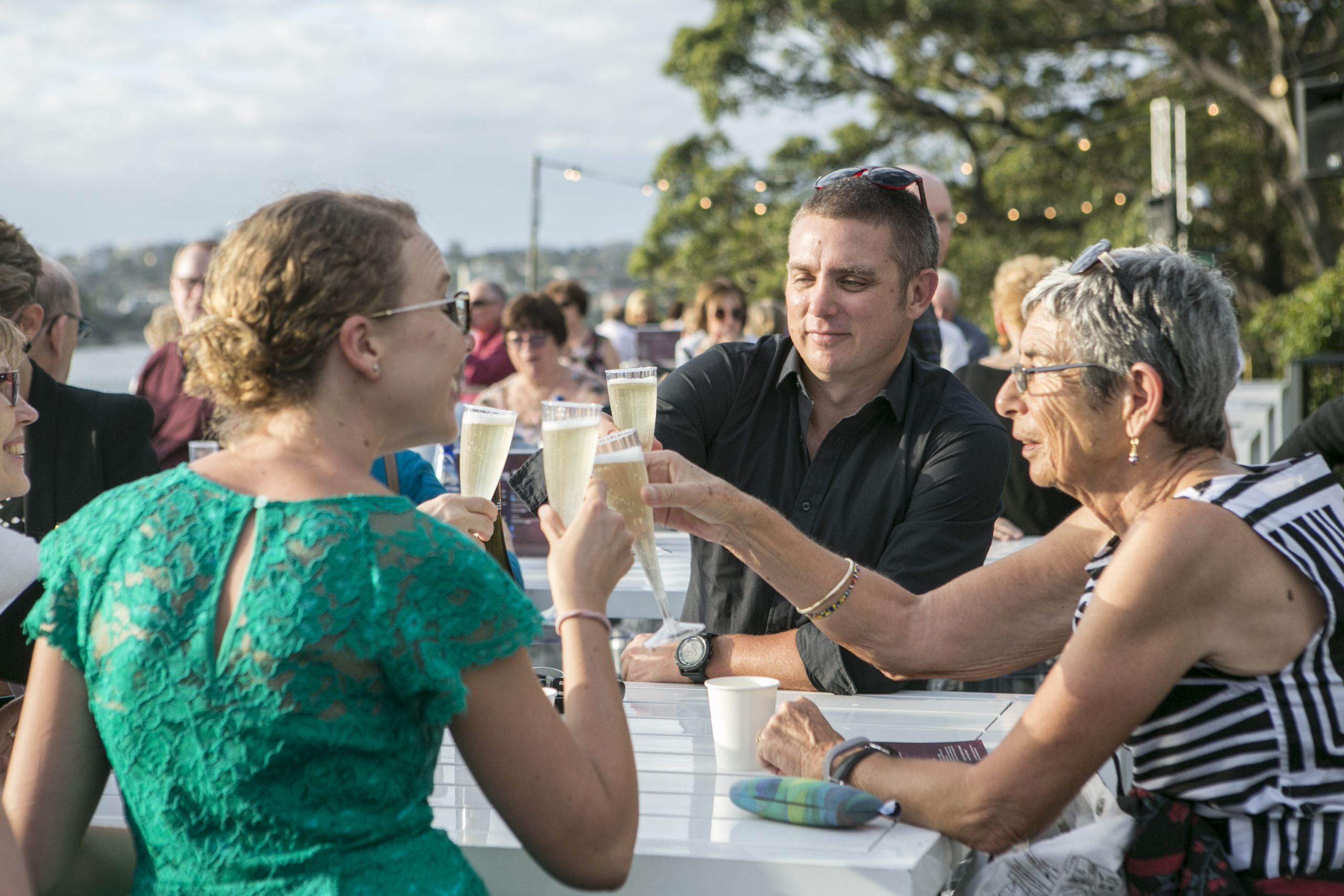 Audience members toasting champagne at Opera Australia's production of West Side on Sydney Harbour in 2019