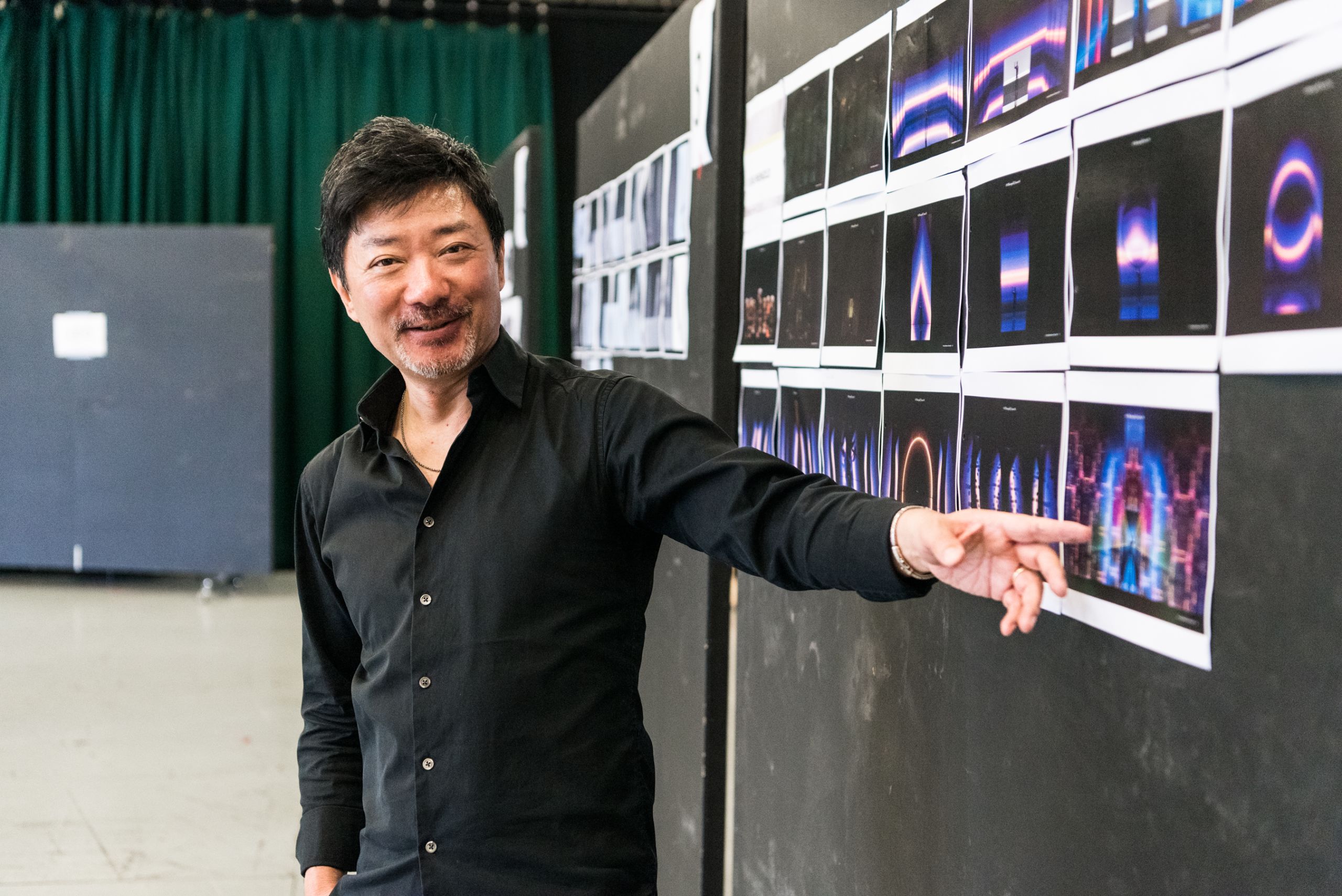 Director Chen Shi-Zheng stands in front of a board with images of futuristic set designs.