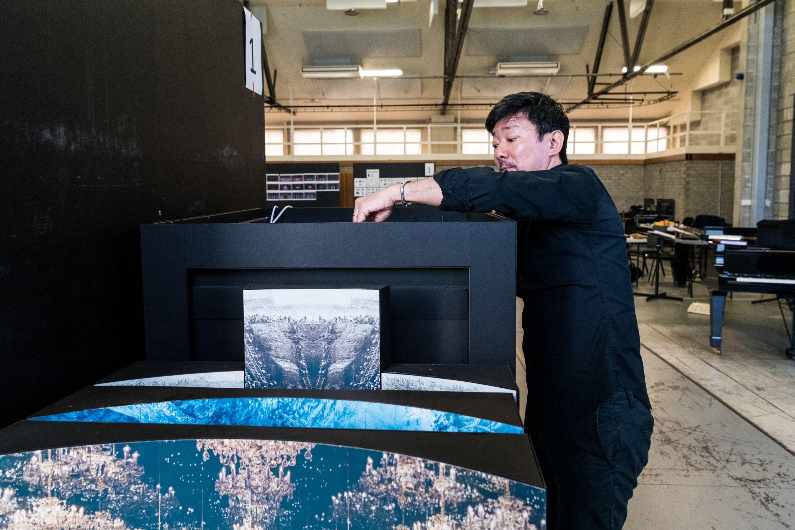 Director Chen Shi-Zheng fiddles with various colourful elements inside a black set model box.