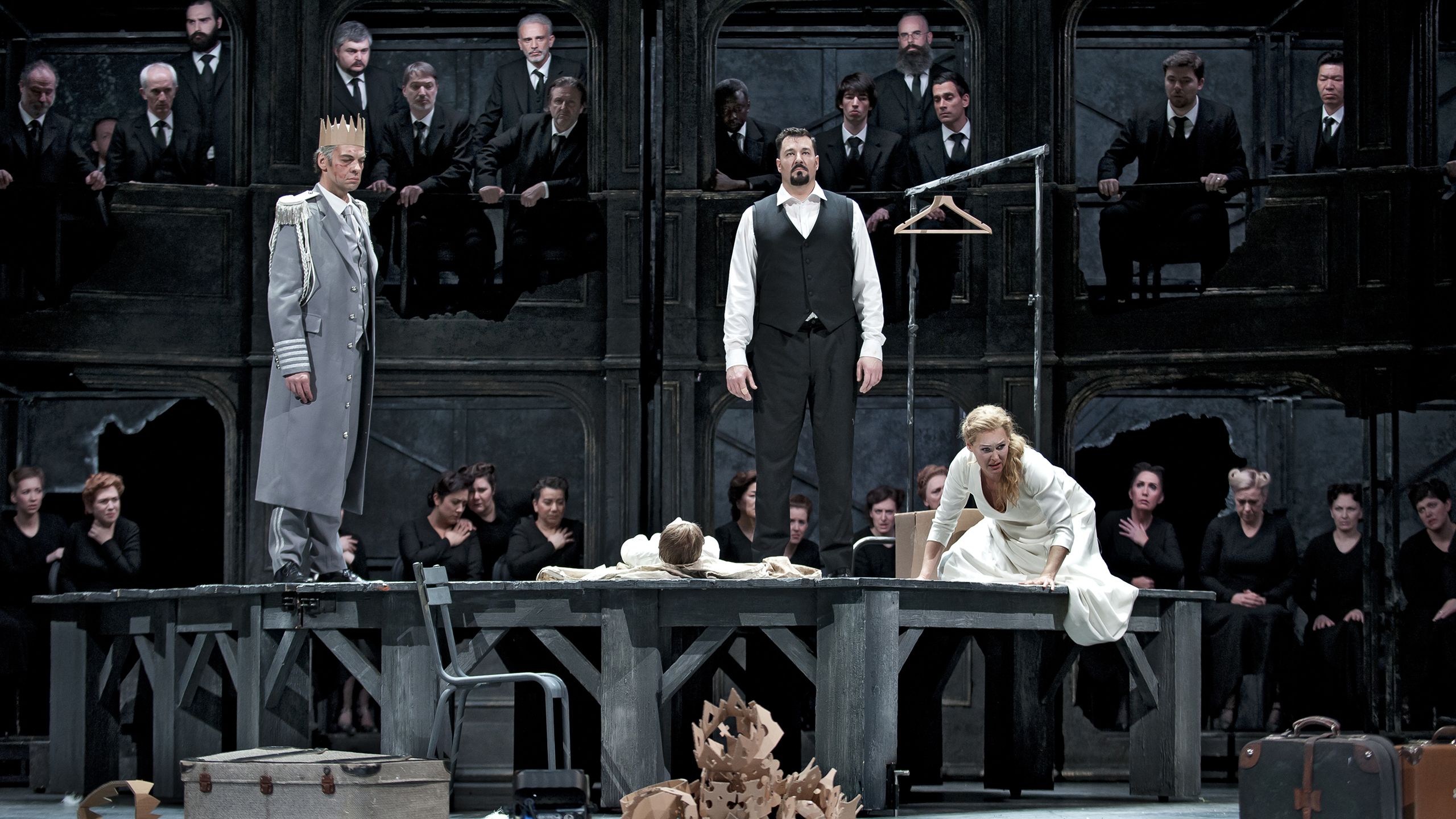 three people standing on a desk in a scene in La monnaie's production of Lohengrin 
