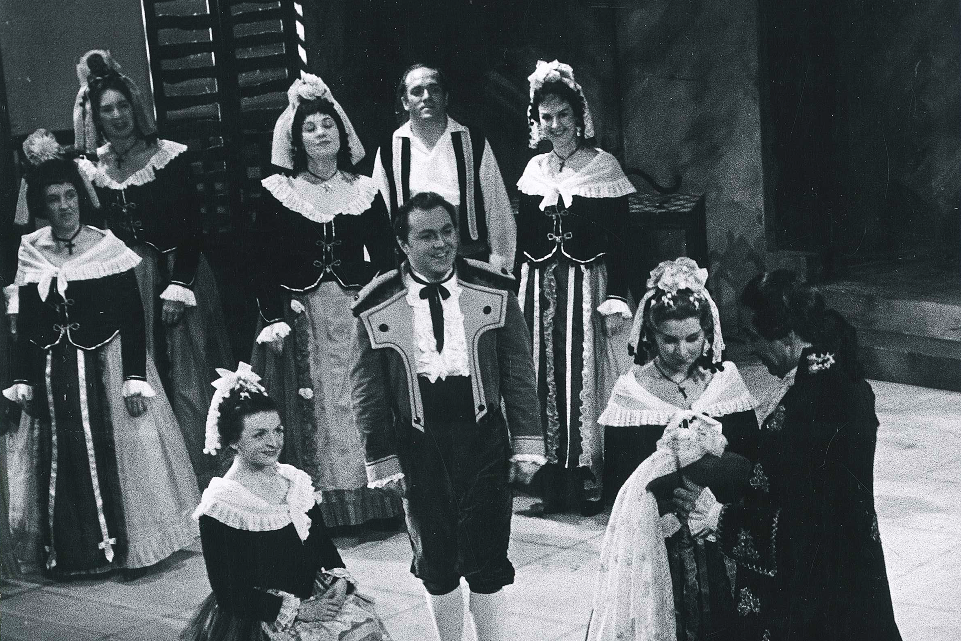 A group of people gather in period costume for a performance of The Marriage of Figaro.