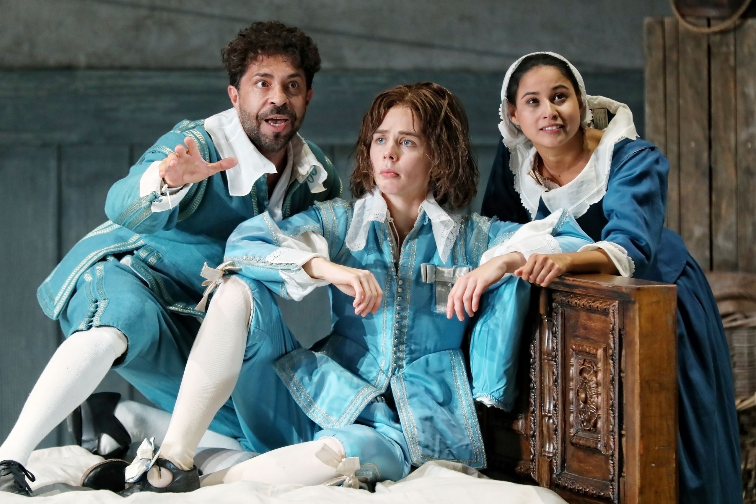 A man and two women sit on stage wearing blue 17th century costumes in a performance of The Marriage of Figaro at the Sydney Opera House.